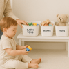 Child with labeled toy storage bins on shelf for home organisation.
