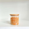 Round bamboo glass jar filled with popcorn kernels, ideal for pantry storage and kitchen organization.