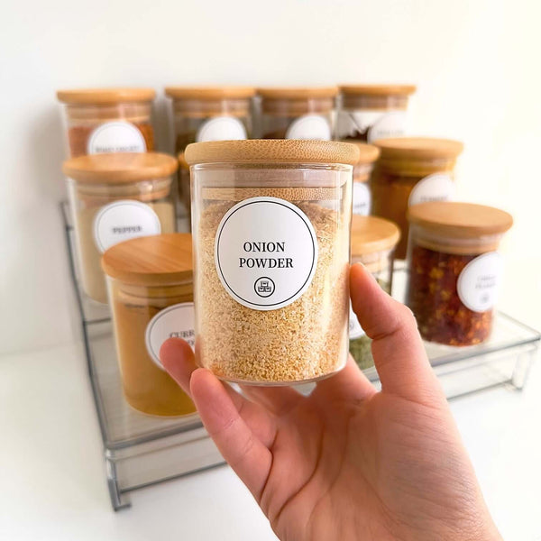 Hand holding bamboo spice jar on acrylic rack, ideal for kitchen storage and organization.