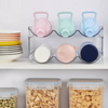 Stacked clear bottle organiser with colorful lids and cereal containers, ideal for kitchen or pantry storage, promoting space efficiency.