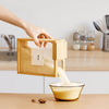 Bamboo food dispenser pouring rice into bowl, ideal for kitchen storage, pantry organisation, stylish bamboo storage, home storage solutions.