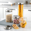 Glass storage jars with stainless lids for kitchen pantry organization holding pasta, grains, roses, and dried fruits.