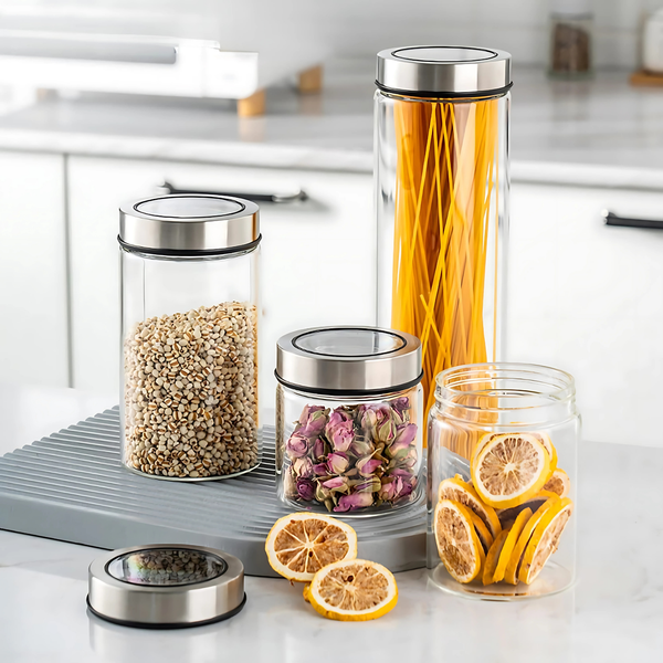 Glass storage jars with stainless lids for kitchen pantry organization holding pasta, grains, roses, and dried fruits.