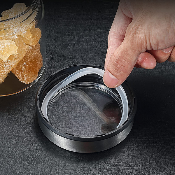 Hand holding glass storage jar with clear stainless lid, ideal for kitchen or pantry organization, featuring airtight seal for freshness.