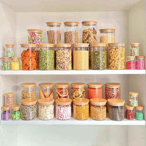 Clear pantry jars with bamboo lids for home organisation, perfect for kitchen storage, featuring dry pasta, cereals, and snacks.