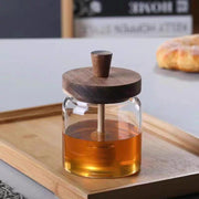 Glass Honey Jar with Wooden Lid & Dipper on a kitchen counter, ideal for kitchen organisation and pantry storage.