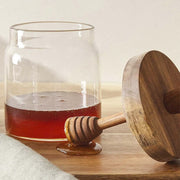 Glass Honey Jar with Wooden Lid & Dipper on kitchen countertop, ideal for kitchen and pantry organisation with glass jars.