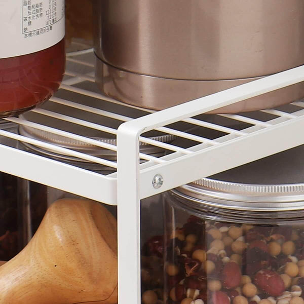 White metal under sink shelf with pantry jars and containers for kitchen storage.