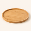 A round bamboo serving tray with a natural light wood grain, shown from a slightly elevated angle on a clean, solid off-white background.