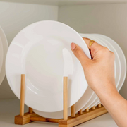 Hand placing a plate in a Bamboo Dish & Pot Lid Rack – 5 Grid used for kitchen organisation, ideal for efficient storage.