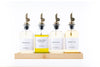 Four round glass oil dispensers with metal spouts on wood tray, ideal for kitchen storage and organisation, featuring sesame oil.