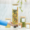 Person holding 2100ml Glass Storage Jar with Bamboo Lid filled with pasta, ideal for kitchen and pantry organisation.