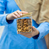 Person holding a jar of almonds with a blurred background