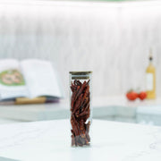 Tall glass jar from the Acacia Square Pantry Collection filled with dried chillies on a kitchen countertop.