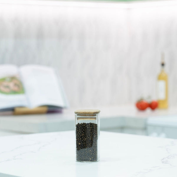 Square Acacia Spice Jar filled with peppercorns on a kitchen countertop, ideal for kitchen organisation and pantry storage.