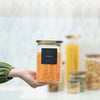 Hand holding one of the Square Acacia Lid Glass Jars – 5 Sizes, perfect for pantry organisation and lentil storage.