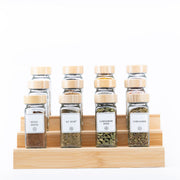 Glass jars filled with assorted spices on a bamboo rack, showcasing the Bamboo Shaker Spice Jar – 120 ml for kitchen organisation.