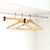 Bamboo coat hangers with black matte hooks for home organisation in a closet; ideal for space-saving and stylish storage solutions.