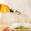 Oil being poured from a bottle into a bowl of salad with a blurred background