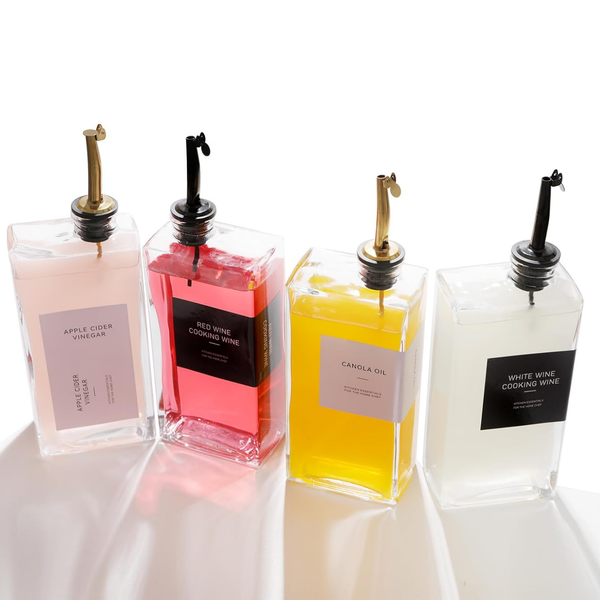 Set of glass oil and vinegar dispensers with labels for apple cider vinegar, red wine, canola oil, and white wine, ideal for kitchen storage.
