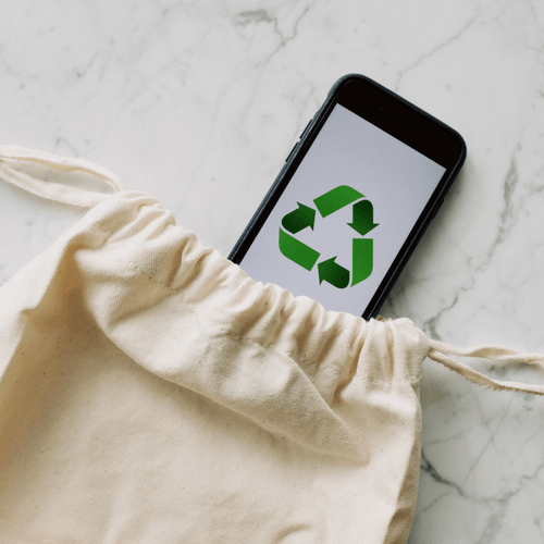 Recycling symbol on smartphone in cotton bag, highlighting eco-friendly storage solutions.