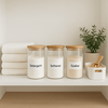 Laundry room shelf with labeled storage jars and neatly stacked towels