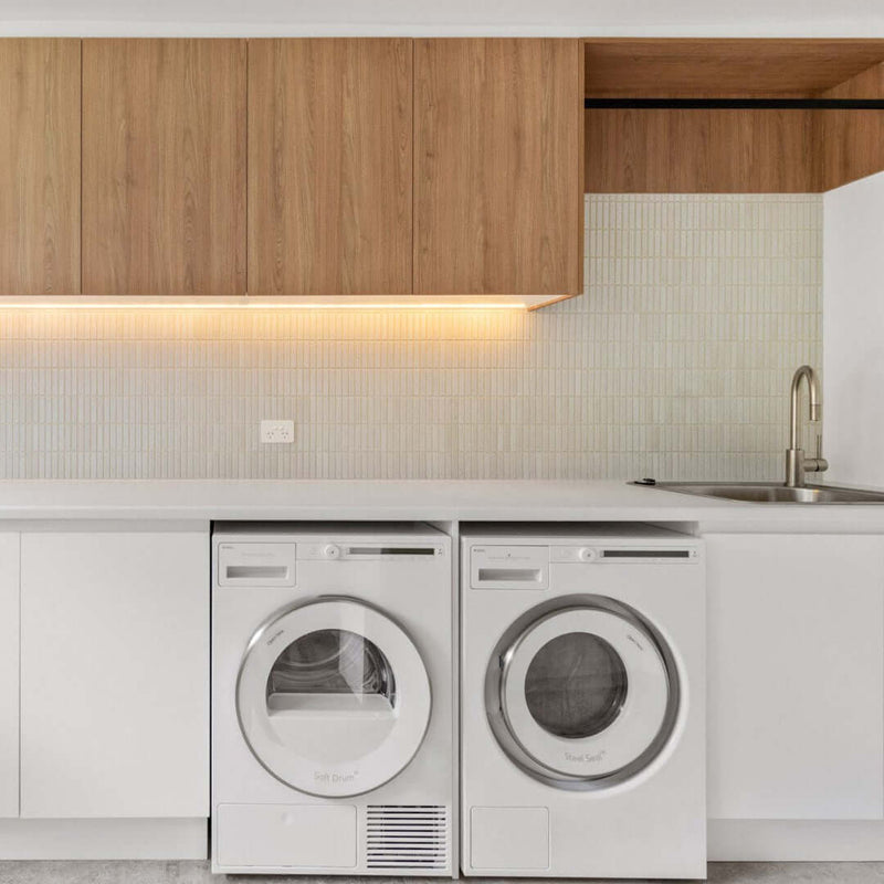 Modern laundry room with washing machine, dryer, and wooden cabinets for home organisation.