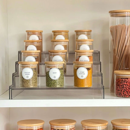 Transparent spice rack with labeled jars for pantry organisation and efficient kitchen storage.