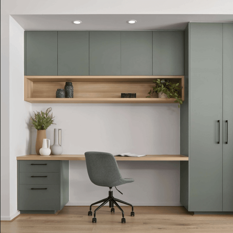 Space-saving home office setup with green cabinets and shelves for organised workspaces.