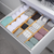 Bamboo expandable drawer dividers organizing towels in a drawer for stylish and practical home storage; ideal for space-saving solutions.