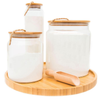Bamboo and glass storage jars set with wooden lids on round tray, ideal for pantry organization and stylish kitchen storage.