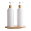 Two white bottles with bamboo caps on a wooden stand against a white background
