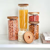 Set of five round glass acacia storage jars for pantry or kitchen organization.