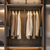 Modern wardrobe with hanging clothes and folded garments on shelves.