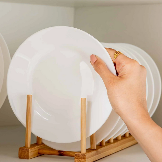 Hand placing a plate in a Bamboo Dish & Pot Lid Rack – 5 Grid used for kitchen organisation, ideal for efficient storage.