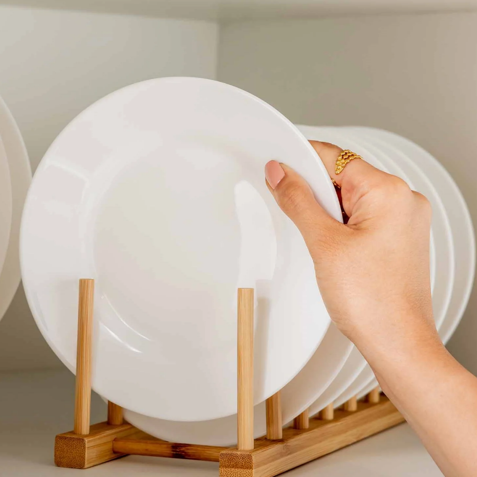 Hand placing a plate in a Bamboo Dish & Pot Lid Rack – 5 Grid used for kitchen organisation, ideal for efficient storage.
