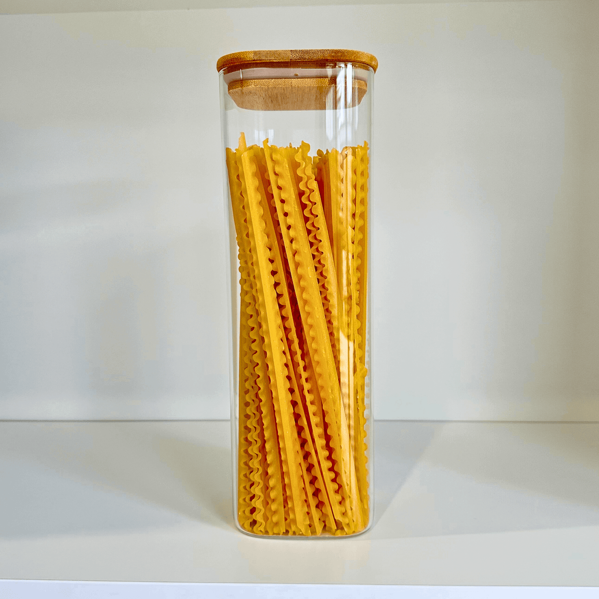 Square Bamboo Glass Pantry Jar Set – 5 Stackable Sizes used for pantry organisation, showcasing kitchen storage of pasta in a glass jar.