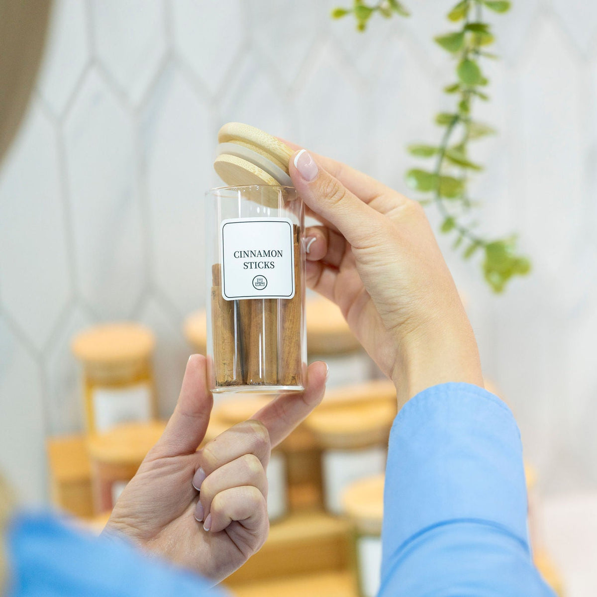 Person using a Round Glass Spice Jar with Bamboo Lid for kitchen storage, enhancing pantry organisation and kitchen aesthetics.