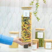 Person holding 2100ml Glass Storage Jar with Bamboo Lid filled with pasta, ideal for kitchen and pantry organisation.