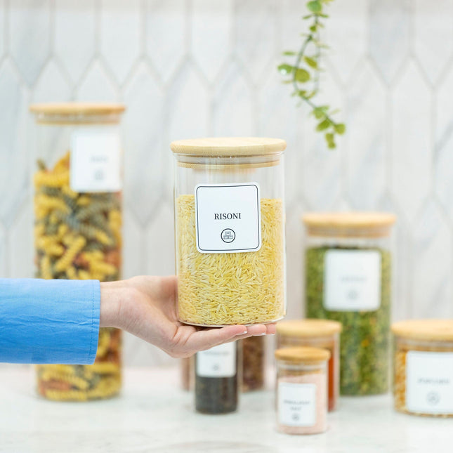 Hand holding a 1250ml Glass Storage Jar with Bamboo Lid, ideal for pantry organisation and storing foods like pasta or grains.