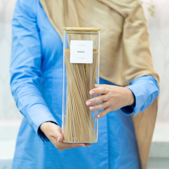 Person holding a Square Glass Jar with Bamboo Lid – 2300ml Pantry Storage filled with pasta for kitchen organisation.