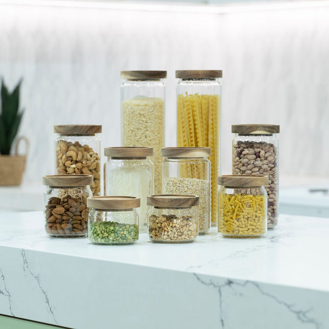 Round Glass Acacia Storage Jar Set – 5 Pack used for pantry organisation on a kitchen countertop, showcasing glass jars with wood lids.