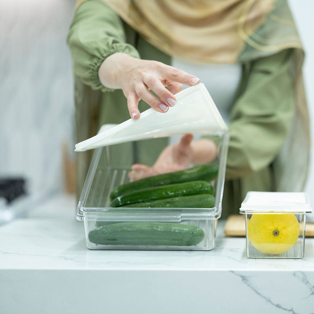Person using Large Airtight Food Storage Container for kitchen organisation, storing cucumbers on marble counter, enhancing pantry organisation.