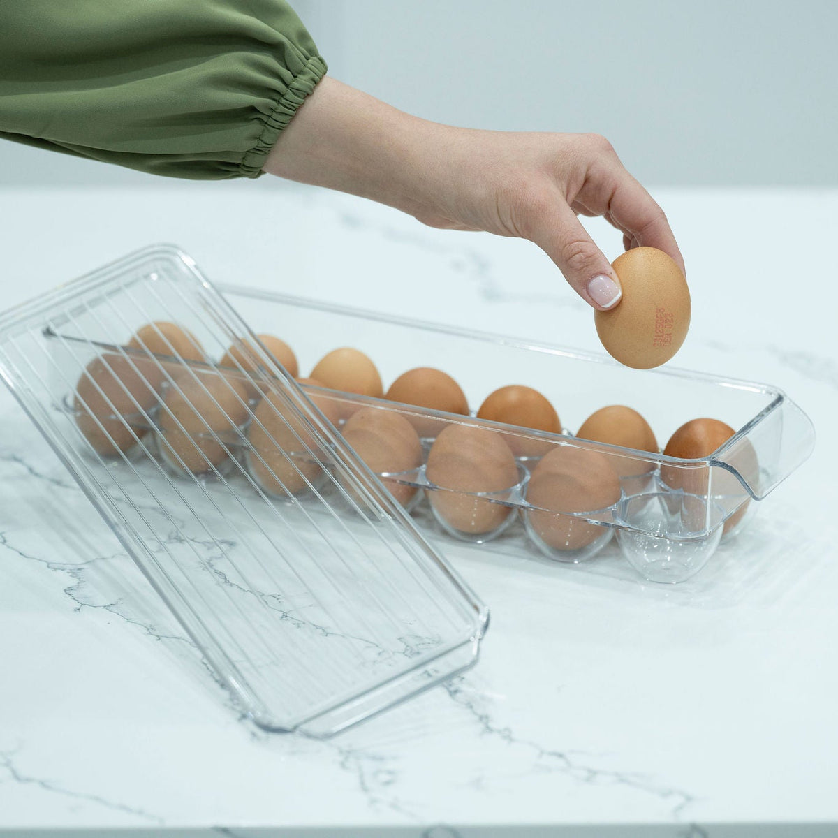 Egg organiser with lid for secure fridge storage, ideal for kitchen organisation. Holds dozen eggs with easy access.