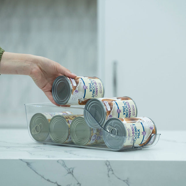 Hand placing a can in a Clear Can Organiser – Small on a kitchen bench, ideal for pantry and fridge storage organisation.