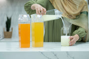 Pouring juice from Clear Drink Container – 2 Liter into glass in kitchen, ideal for home storage organisers Australia