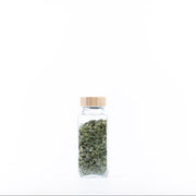 Glass jar with bamboo lid, filled with dried herbs, perfect for kitchen organisation and storage. Ideal Bamboo Shaker Spice Jar – 250 ml.