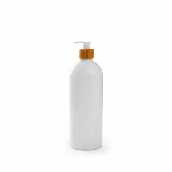 White bottle with a wooden pump on a bathroom counter with plants in the background