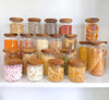 21 Acacia glass jars for pantry storage, filled with assorted kitchen essentials.