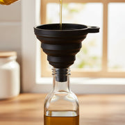 Black Foldable Silicone Funnel for Jars & Liquids used for kitchen organisation, pouring oil into a glass jar.
